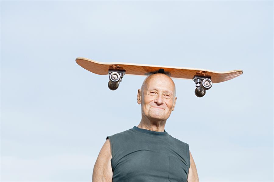 Older man with skateboard balanced on his head.