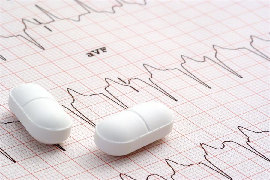 White pills lying on a chart showing heart rate patterns.