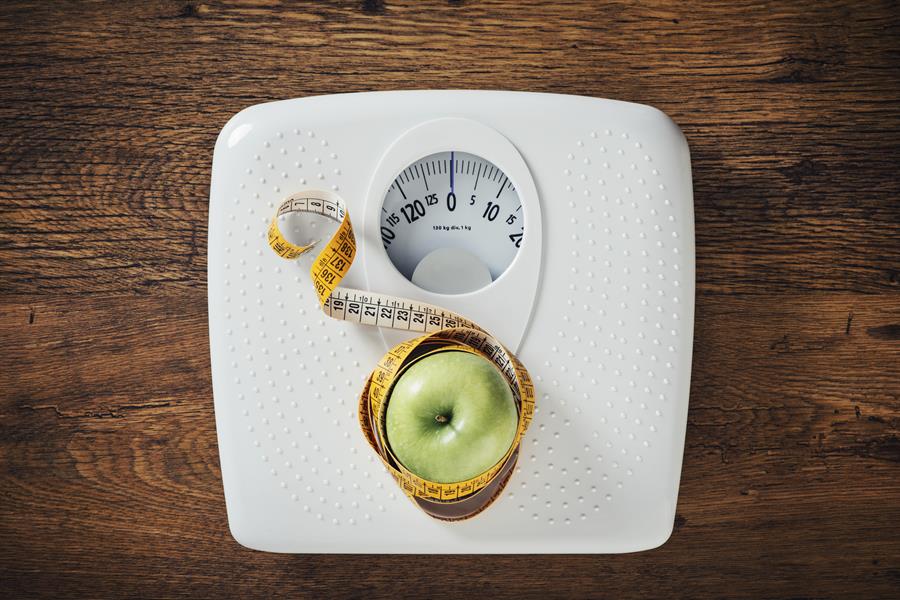 Weighing scale with apple and measuring tape.