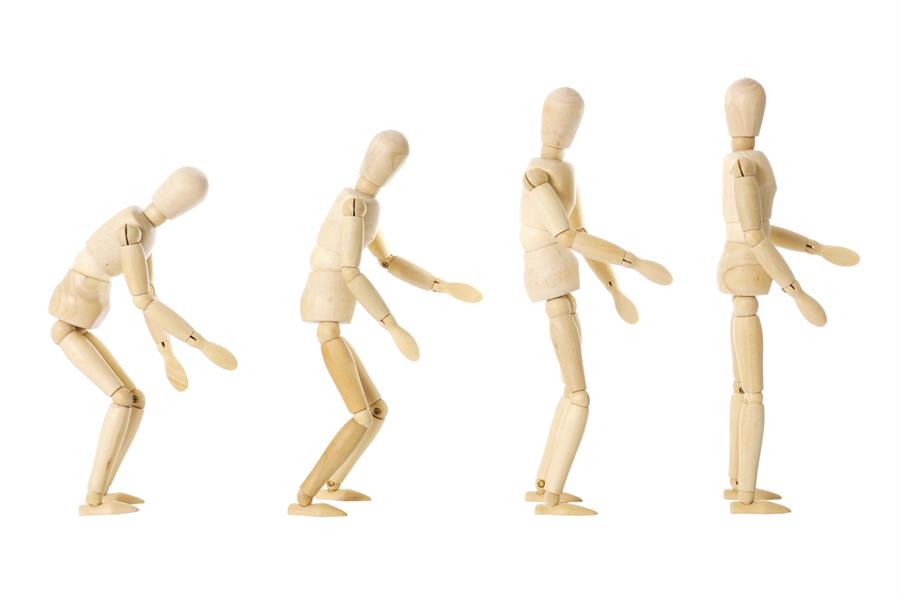 Four wooden figures in a row progressively standing up straight.