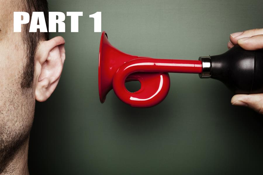 Close up of a large red horn held up to a mans ear.