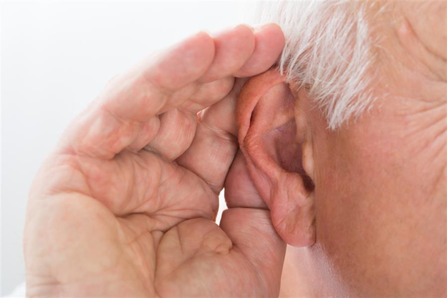 Close-up of a senior man with hand cupped over his ear to try and hear better.