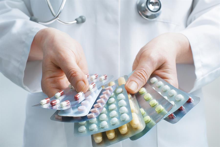 Hands of pharmacist holding several different types of medication.