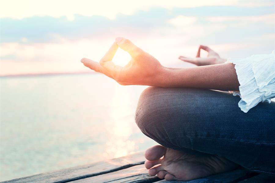 Adult hand resting on knee in meditation position.