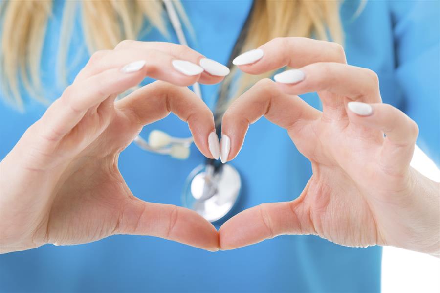 Close up of nurses hands with fingers forming a heart.