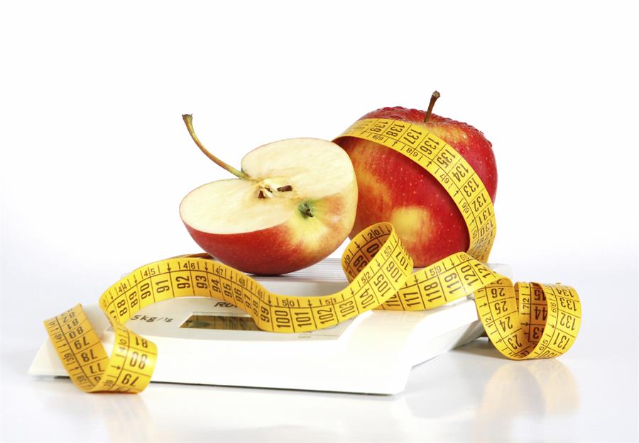 measuring tape and apple sitting on a weighing scale