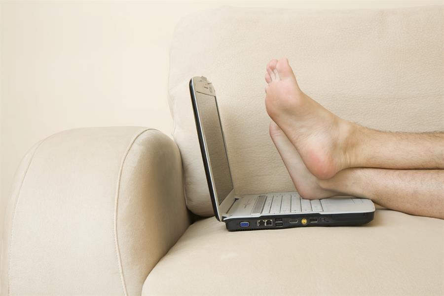 Legs crossed on an open laptop placed on a couch.