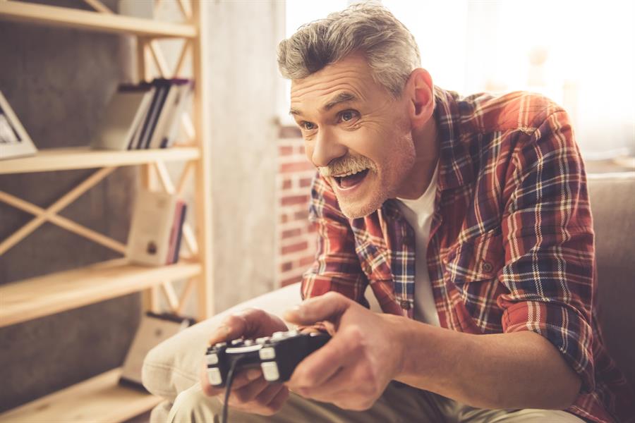 Older man excited playing video game on couch.