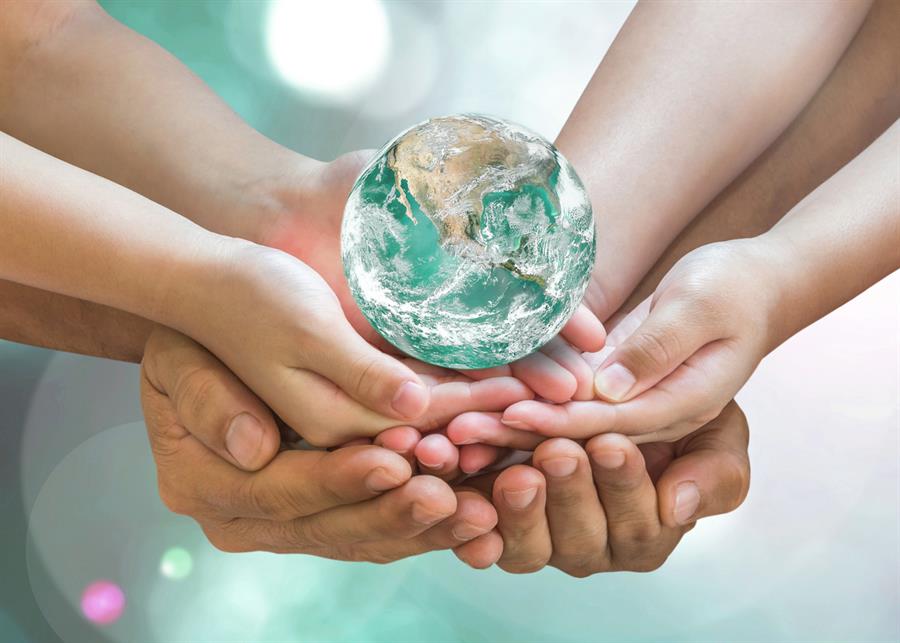 Green globe of earth being supported and held by multiple pairs of hands.