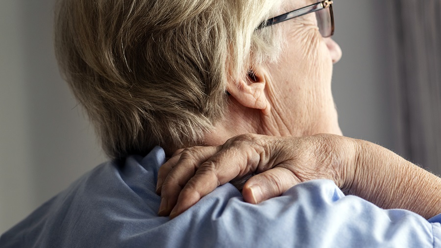 Older adult grasping at shoulder pain with pain from a frozen shoulder