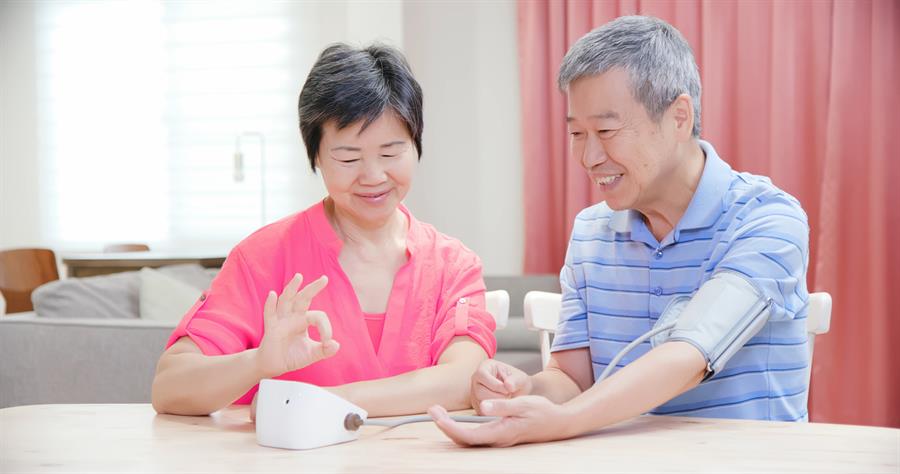 Older adult couple measuring their blood pressure at home. 