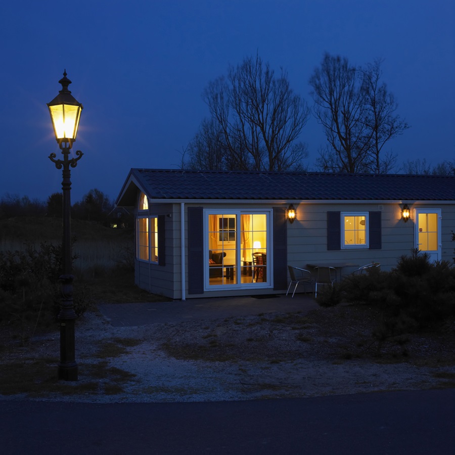 Street view of an illuminated house at night-time and a street light.