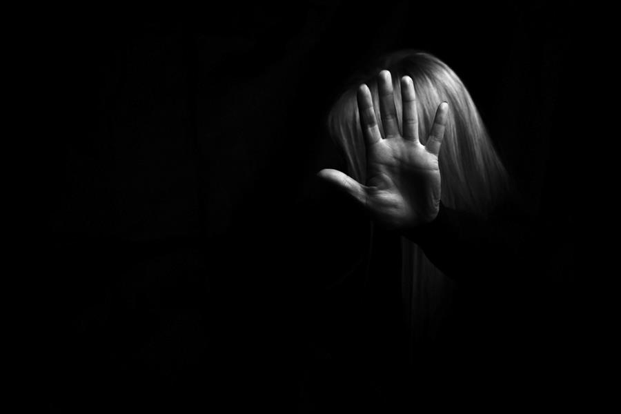 Woman holding out hand to gesture stop infront of her face in black and white.