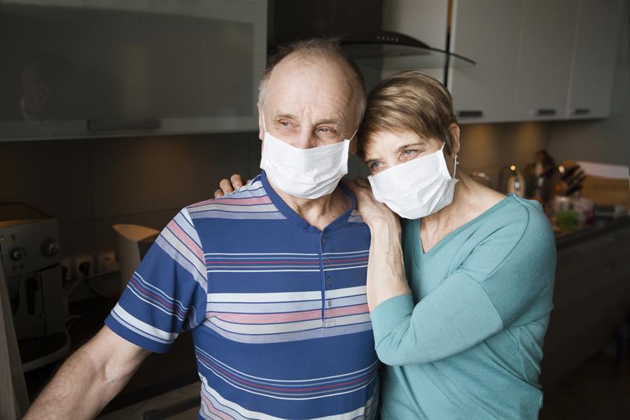 Senior couple wearing medical face masks in their home.