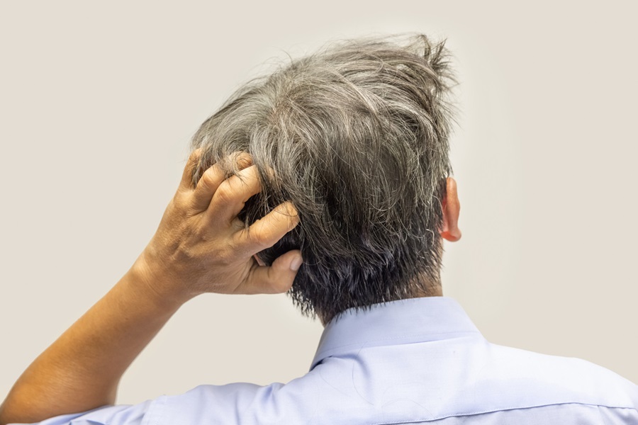 Older man scratching dandruff from the back of his head