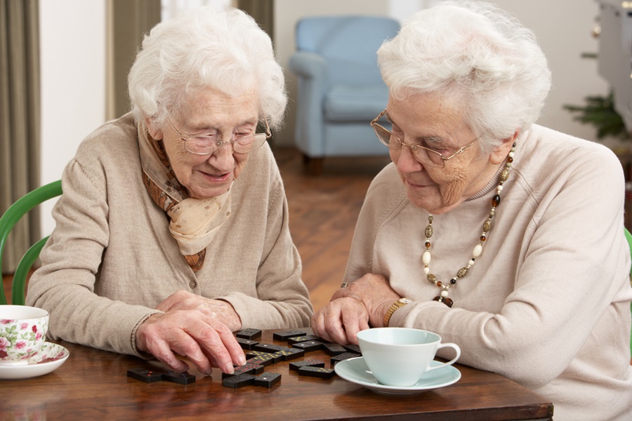 Two senior women playing dominoes at a care center