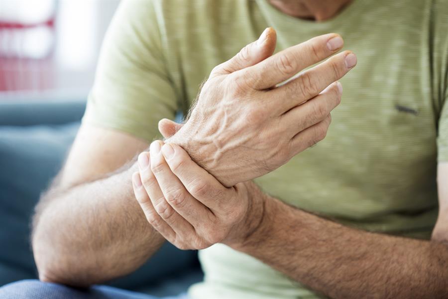 Older adult male holding his wrist. 