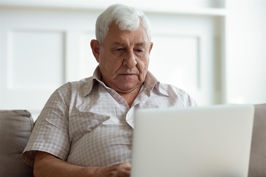 Senior man looking serious and concerned at his laptop.