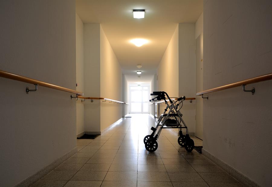 A lone walking assistance device in a long hallway of a nursing home.