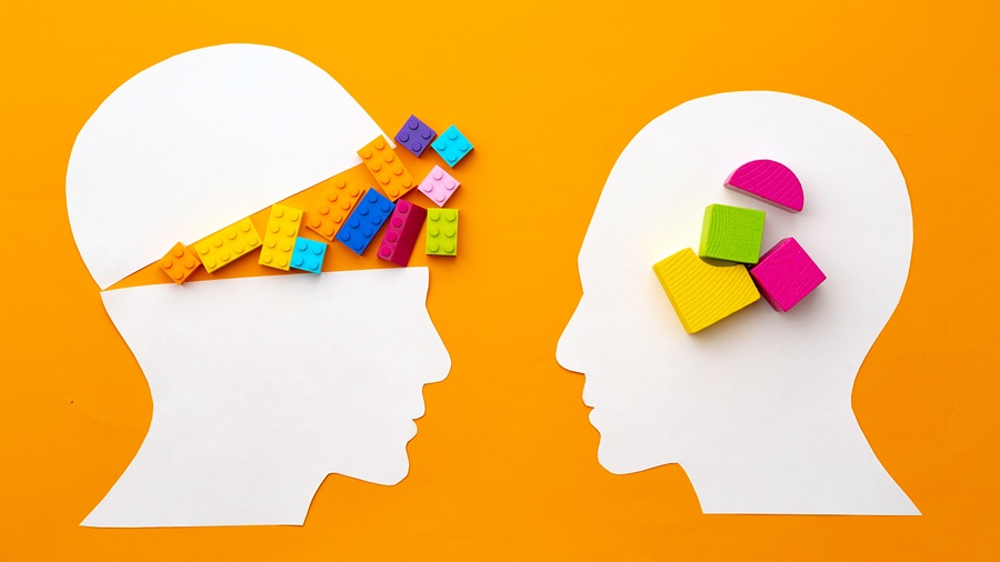 Silhouettes of paper heads with blocks signifying cognitive impairment