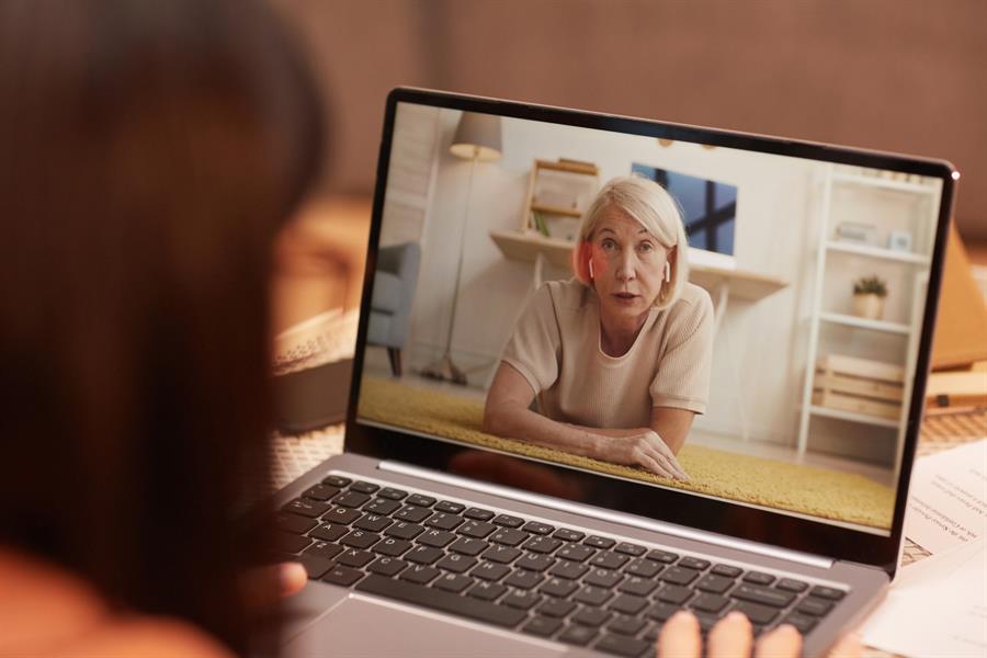 Older adult female having a virtual meeting with her peer using a laptop and videoconferencing technology.    