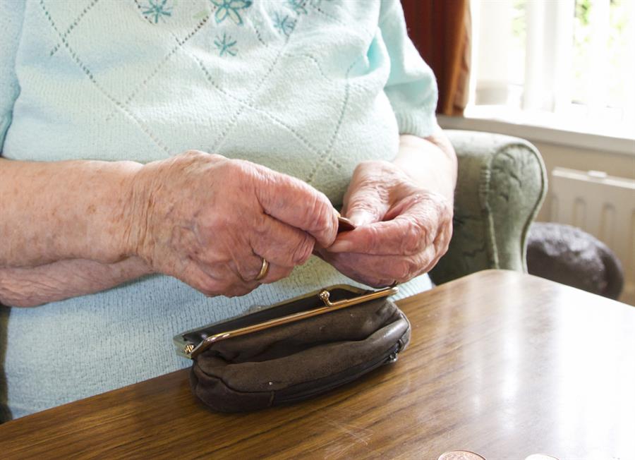 Close up of a woman's hands counting coins on a table out of a brown purse.