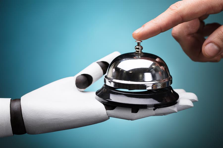 Person's hand ringing a service bell held up by a robot on a turquoise background.